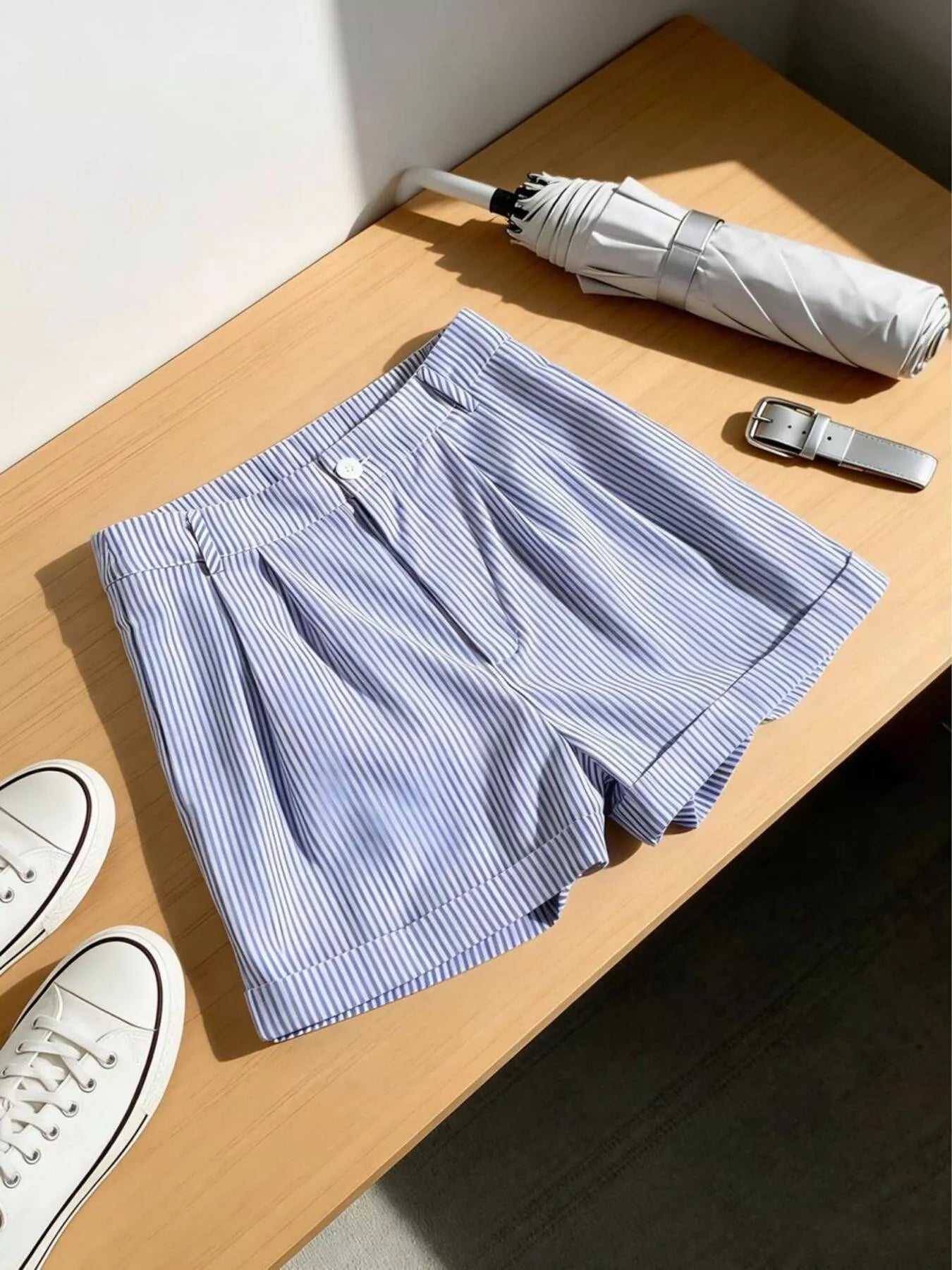 Blue striped boxer shorts on a wooden surface with an umbrella and sneakers.