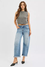 Woman wearing a gray sleeveless top and light blue jeans on a white background