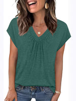 Woman wearing a green short-sleeve top with a plain background
