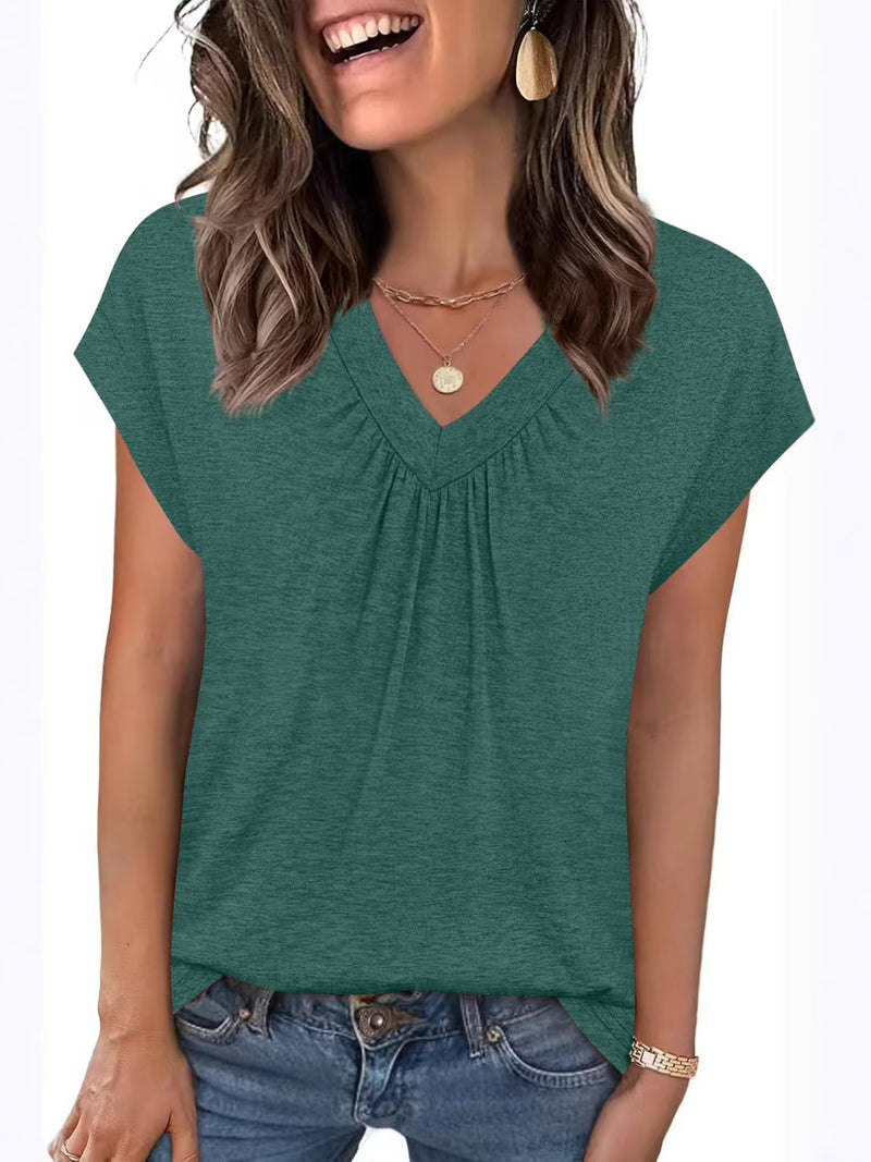 Woman wearing a green short-sleeve top with a plain background