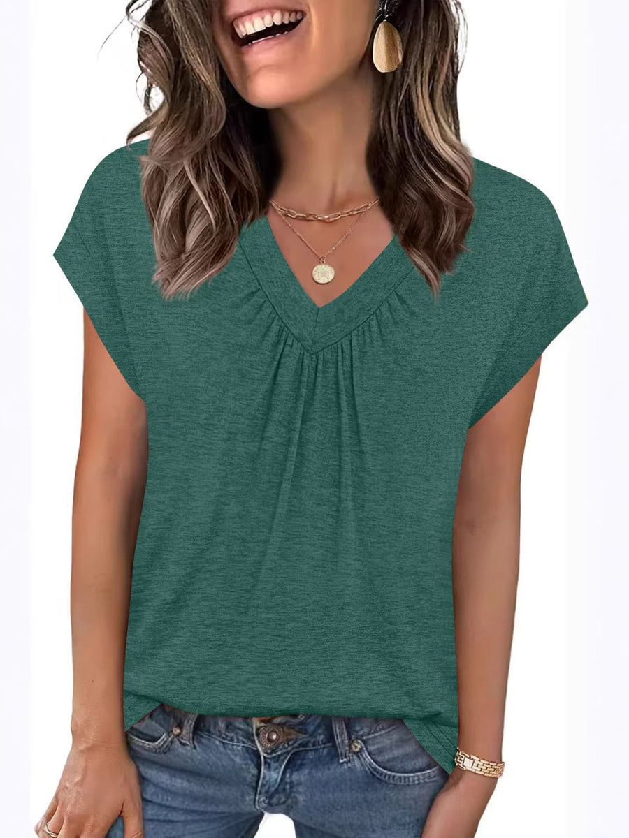 Woman wearing a green short-sleeve top with a plain background