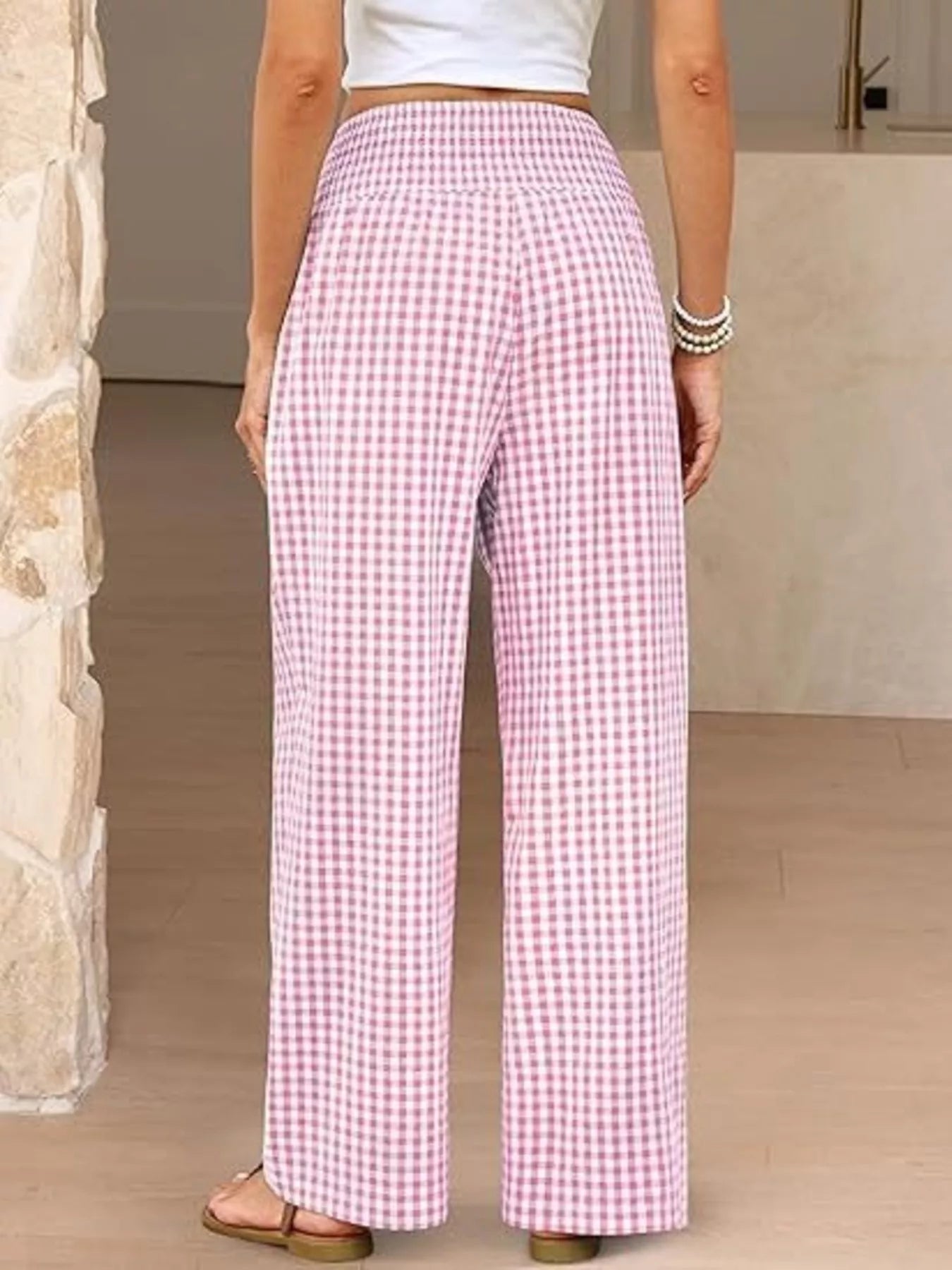 Person wearing pink checkered pants in a neutral setting