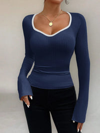 Woman wearing a blue ribbed long-sleeve top against a neutral background