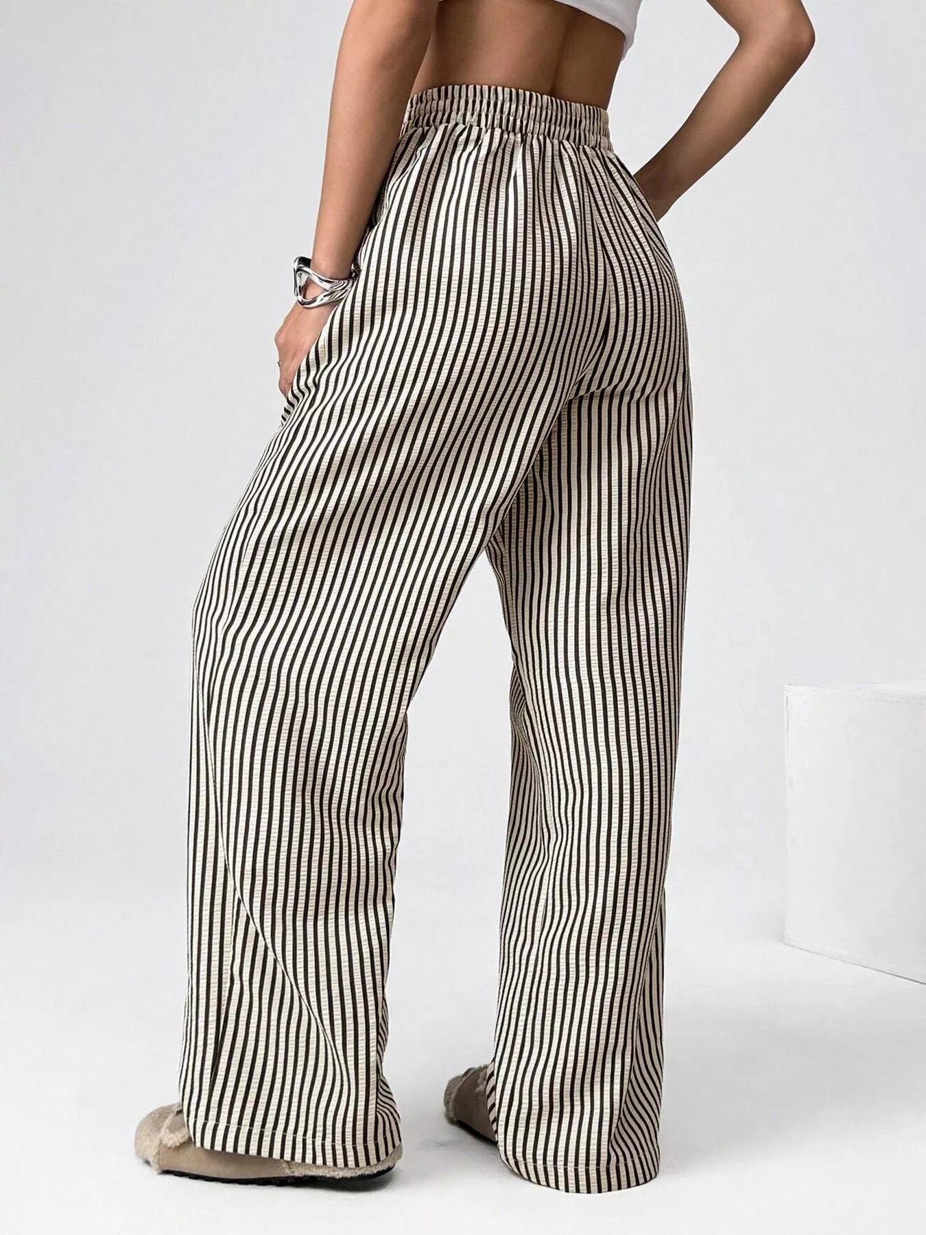 Person wearing striped wide-leg pants on a white background