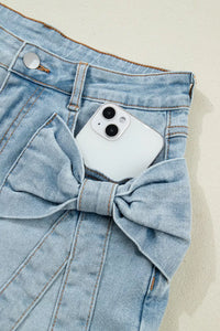 White phone in a blue denim pocket with a bow detail