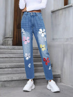 Person wearing blue jeans with colorful floral patches on a stone staircase.