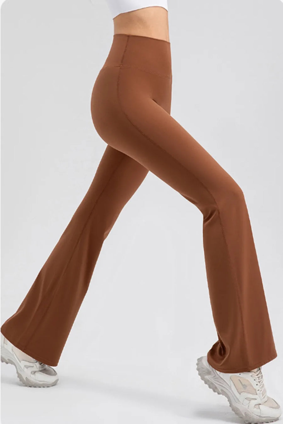 Brown flared pants worn by a person on a white background