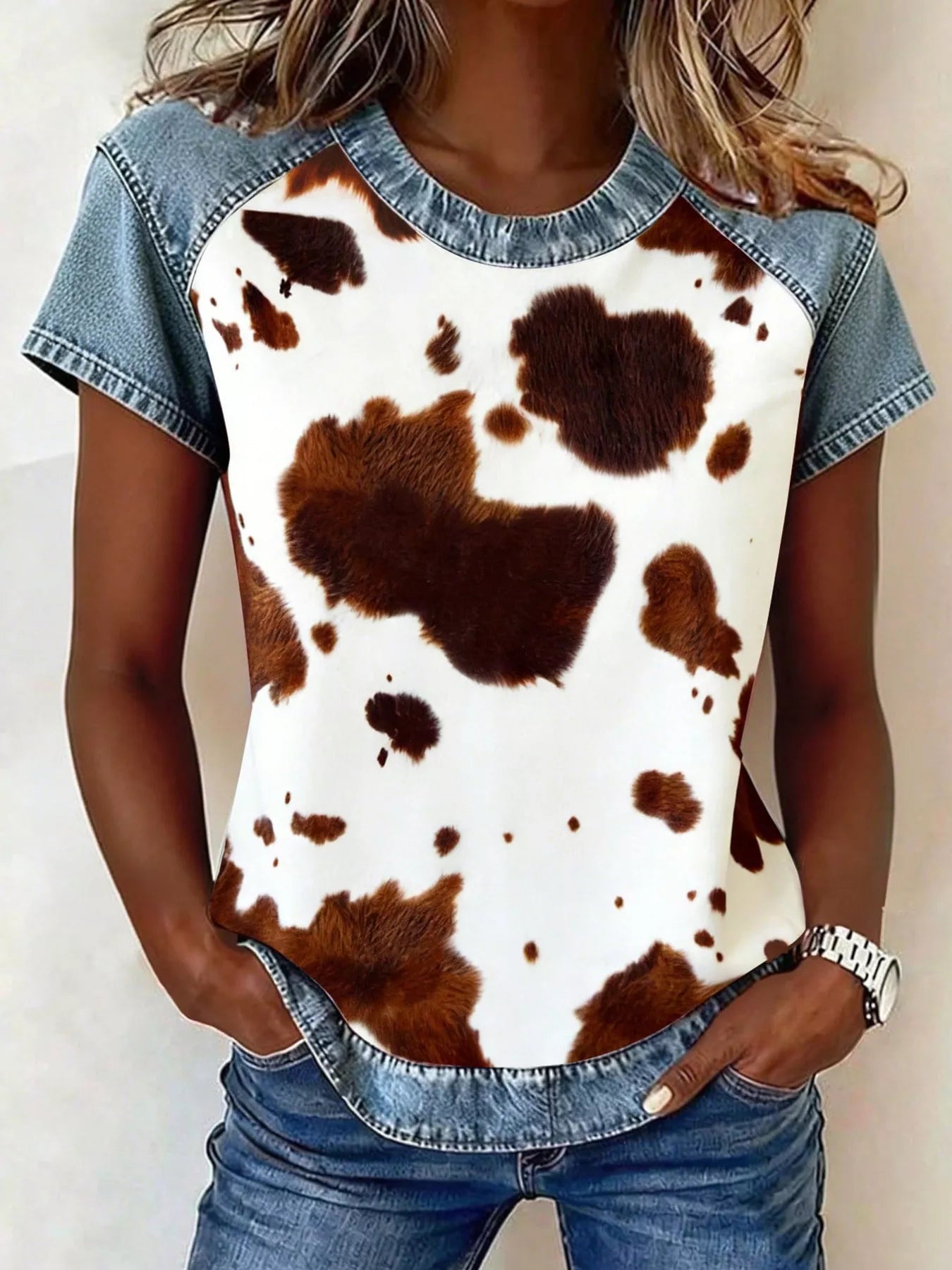 Person wearing a cow print shirt with denim sleeves and pants.