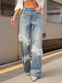 Person wearing light blue jeans with lace details at a train station.