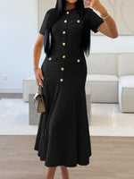 Woman wearing a black dress with gold buttons in an indoor setting