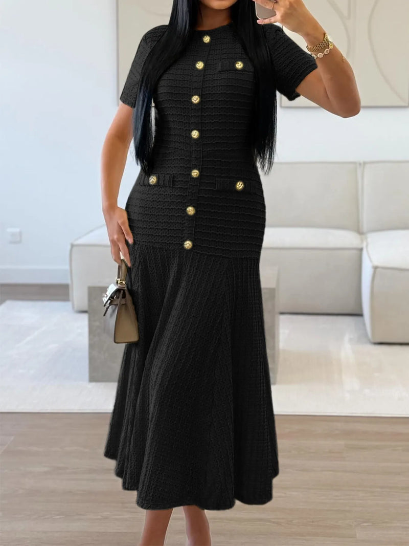 Woman wearing a black dress with gold buttons in an indoor setting