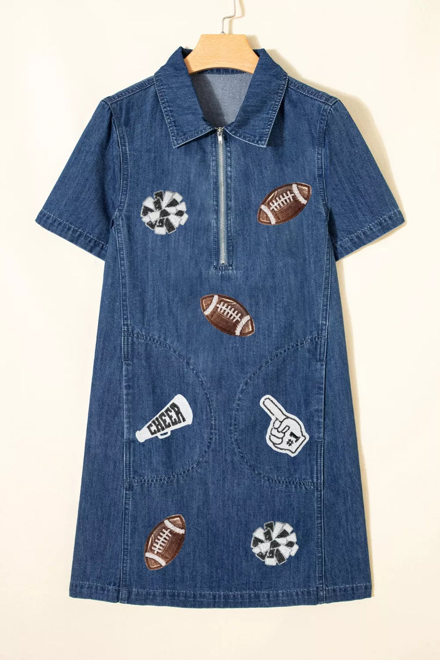 Blue denim dress with sports-themed patches on a beige background