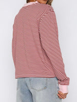 Red and white striped long-sleeve shirt worn by a person on a plain background