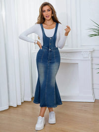 Woman wearing a denim dress with a white long-sleeve top in a room with white curtains and a white fireplace.