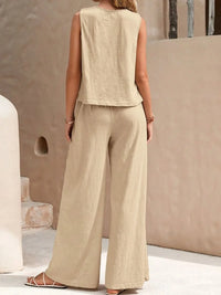 Woman wearing a beige sleeveless top and wide-leg pants in an outdoor setting.