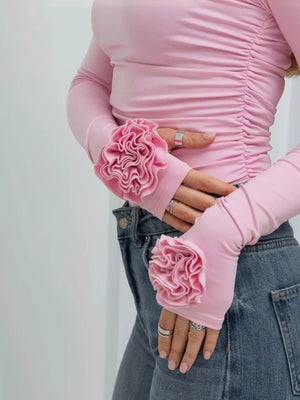 Person wearing pink long-sleeve top with floral elbow pads against a white background