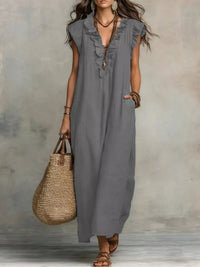 Woman wearing a gray sleeveless dress holding a woven bag against a neutral background