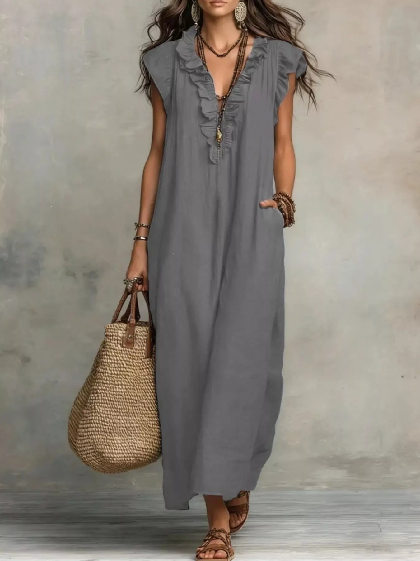 Woman wearing a gray sleeveless dress holding a woven bag against a neutral background