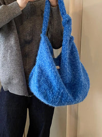 Person holding a blue textured handbag against a neutral background