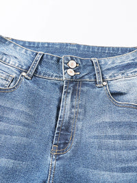 Close-up of a blue denim jeans waistband with buttons and stitching details.