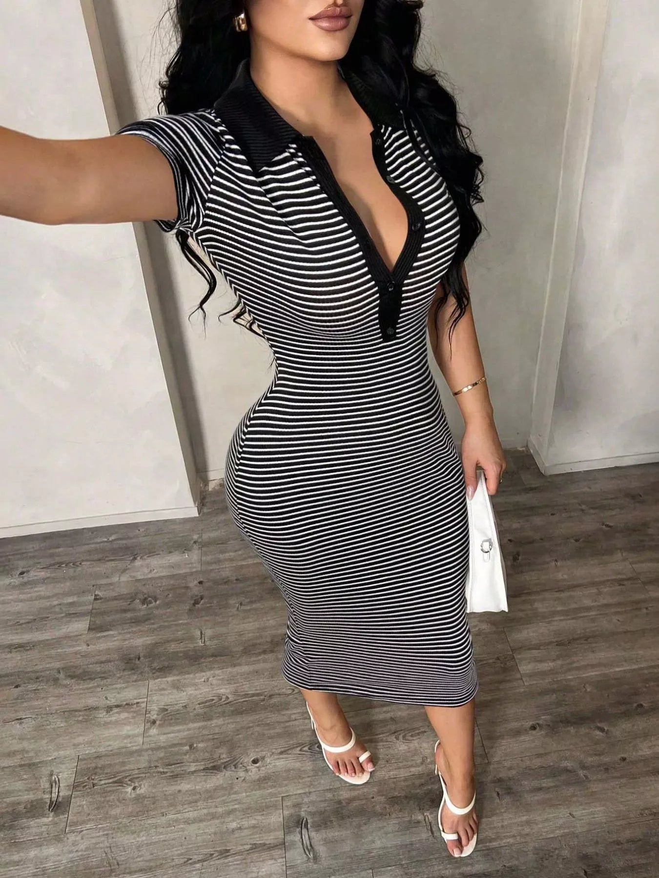 Woman wearing a black and white striped dress with a deep neckline.