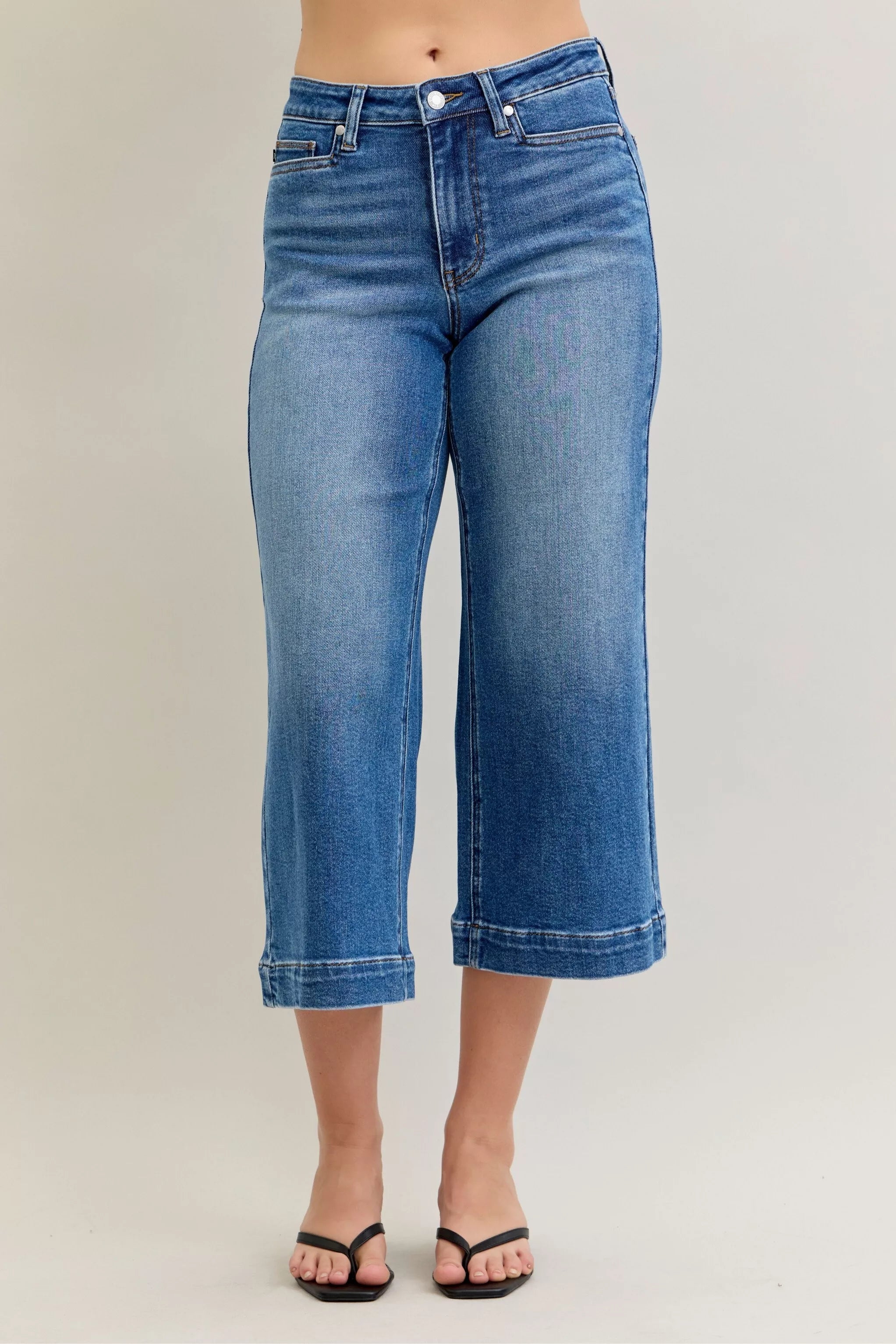 Blue jeans worn by a person on a plain background