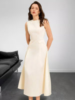 Woman wearing a white dress in a minimalistic room with a black sofa.
