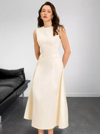 Woman wearing a white dress in a minimalistic room with a black sofa.