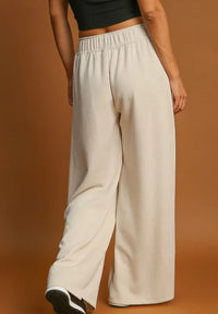 Person wearing beige wide-leg pants on a brown background