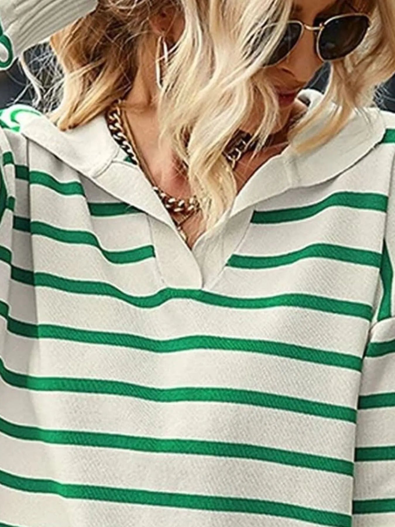 Person wearing a green and white striped shirt with a blurred background