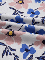 Close-up of floral fabric with pink, blue, and black flowers on a white background