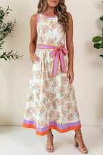 Woman wearing a floral dress with a belt, standing against a neutral background.