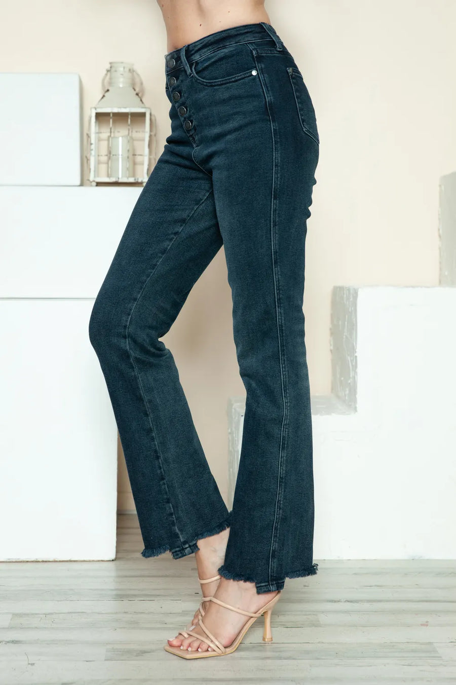 Person wearing dark blue jeans with a neutral background