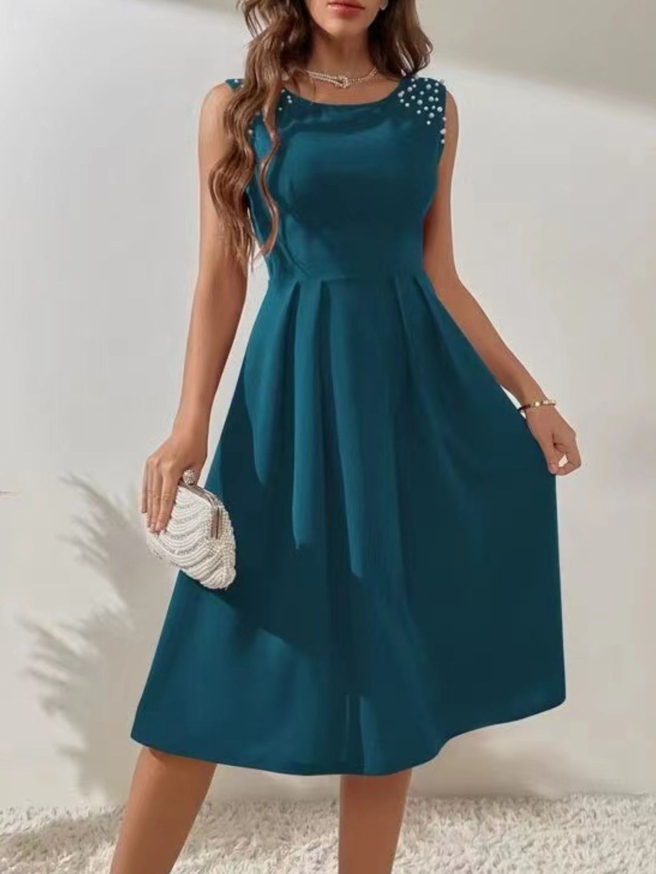 Teal dress with pearl embellishments on a white background