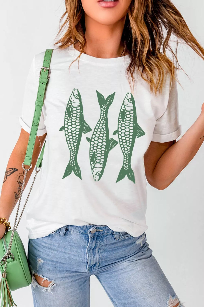 Person wearing a white t-shirt with green fish graphics, holding a green handbag.
