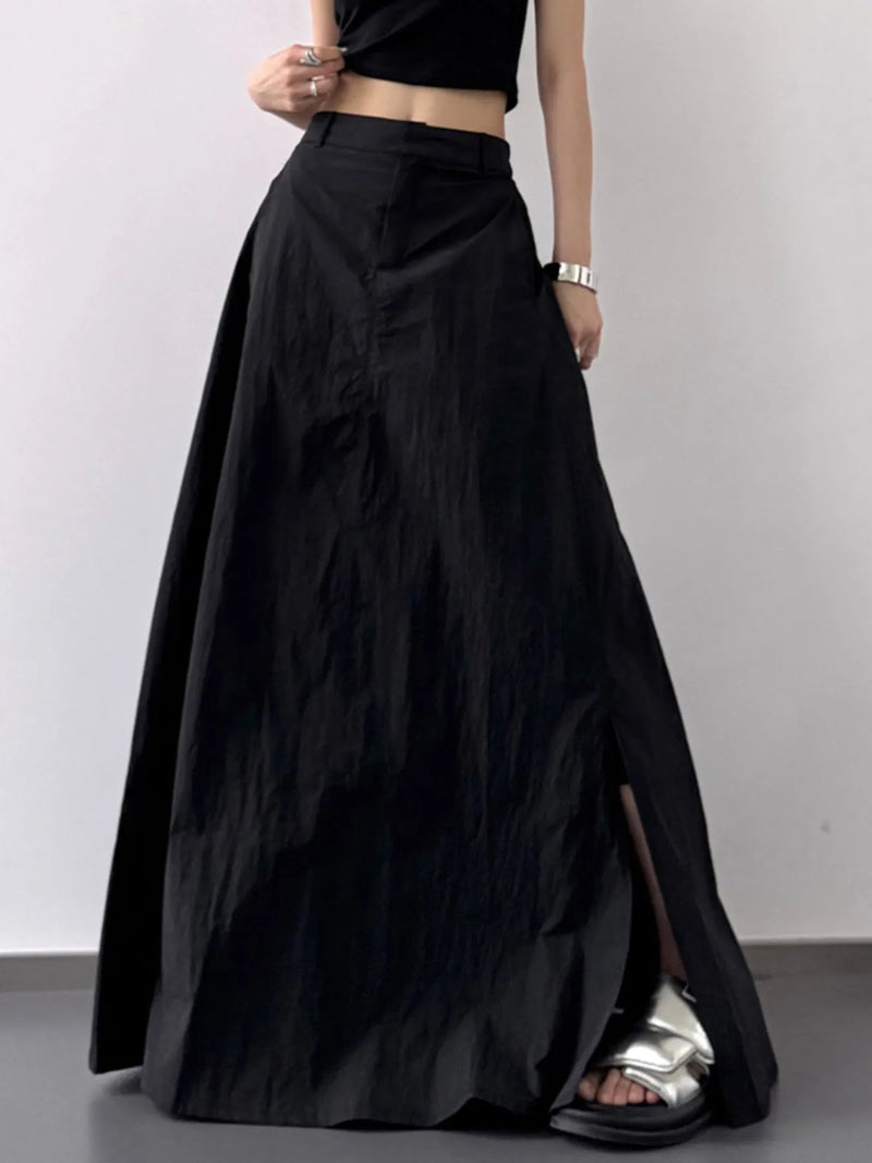 Person wearing a long black skirt with a plain background