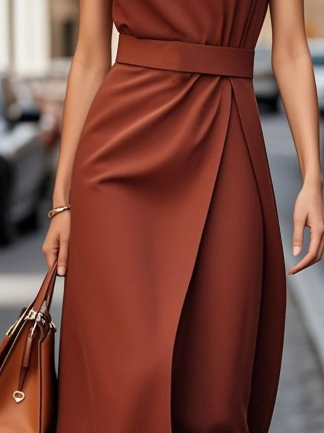 Brown dress with a belt and matching handbag on a blurred street background