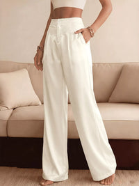 Person wearing white wide-leg pants standing in a living room.