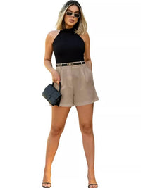 Woman wearing a black sleeveless top and beige shorts on a white background