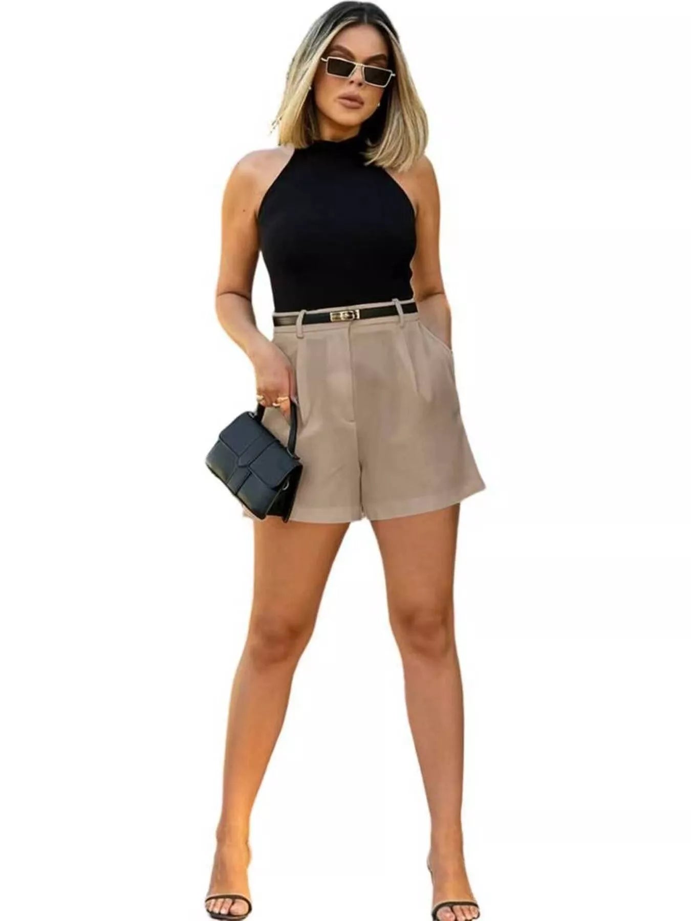 Woman wearing a black sleeveless top and beige shorts on a white background