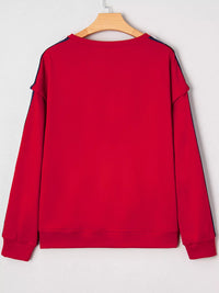 Red sweatshirt on a wooden hanger against a light gray background