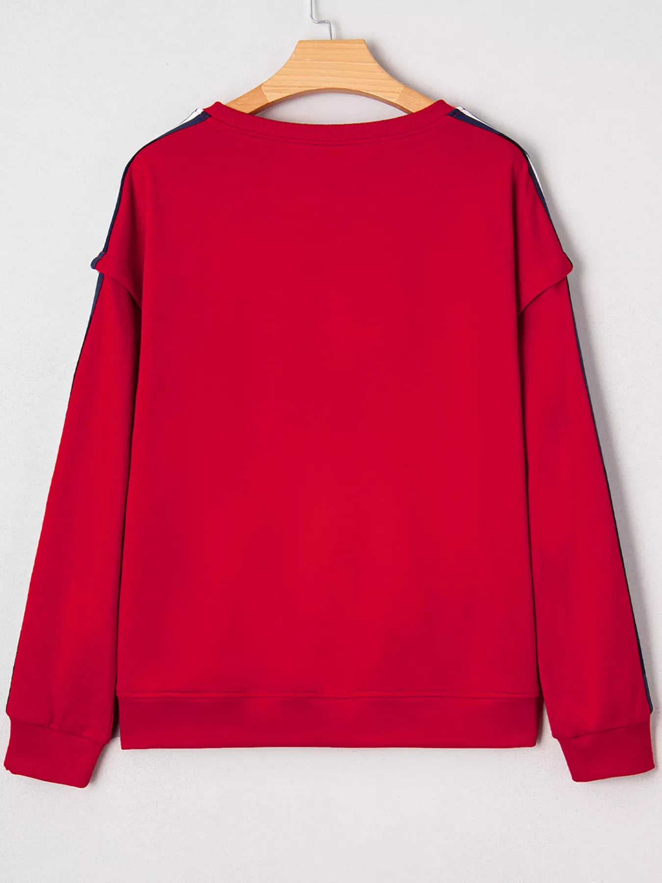 Red sweatshirt on a wooden hanger against a light gray background