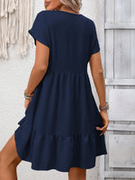Woman wearing a navy blue dress against a light wooden panel background