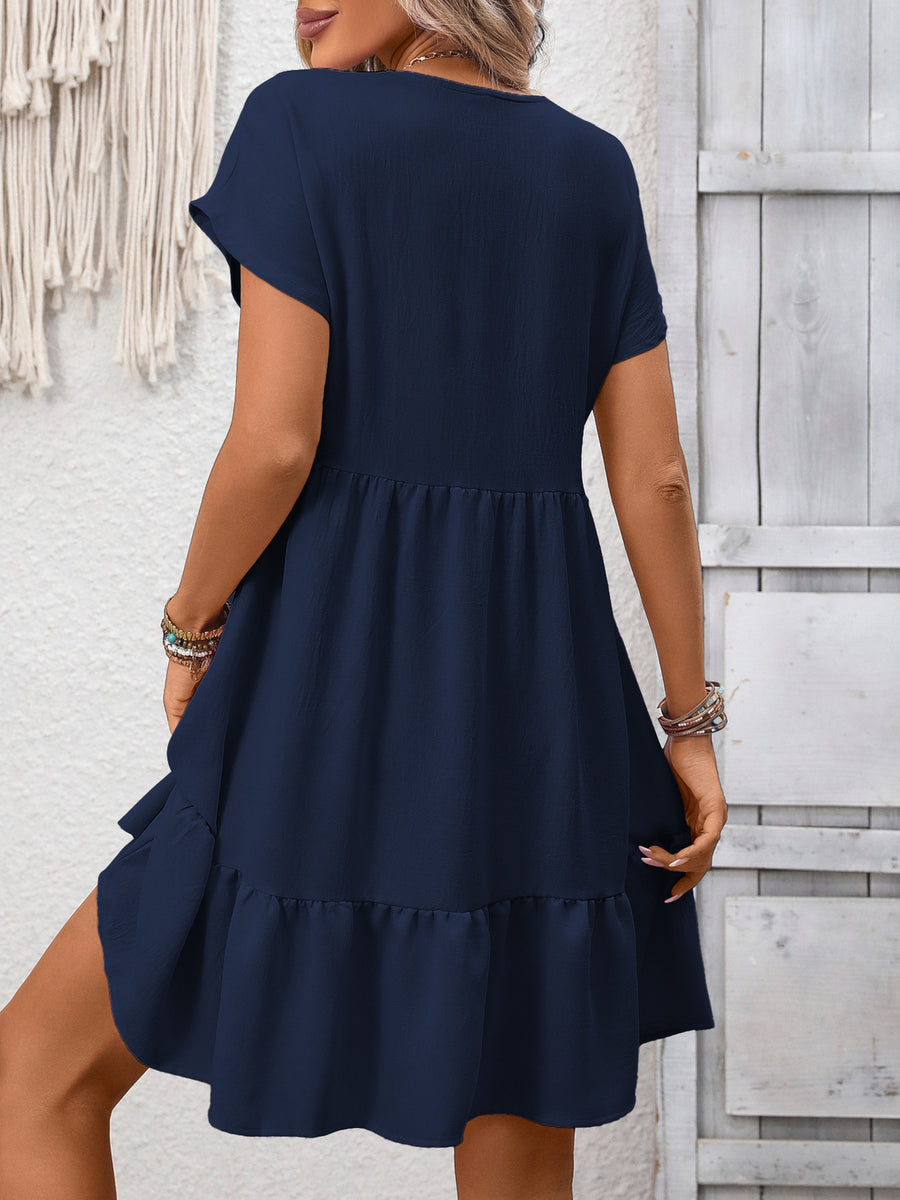 Woman wearing a navy blue dress against a light wooden panel background