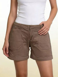 Brown shorts worn with a white top on a plain background