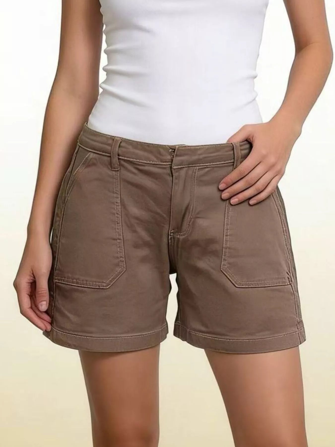 Brown shorts worn with a white top on a plain background