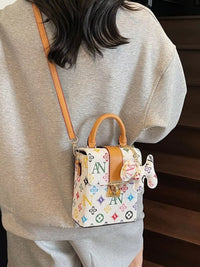 Person wearing a colorful patterned handbag with a brand logo.