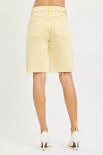 Light yellow denim shorts worn by a person on a white background