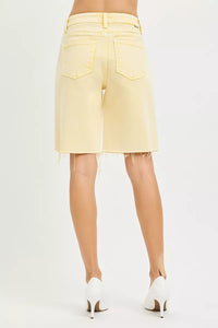 Light yellow denim shorts worn by a person on a white background