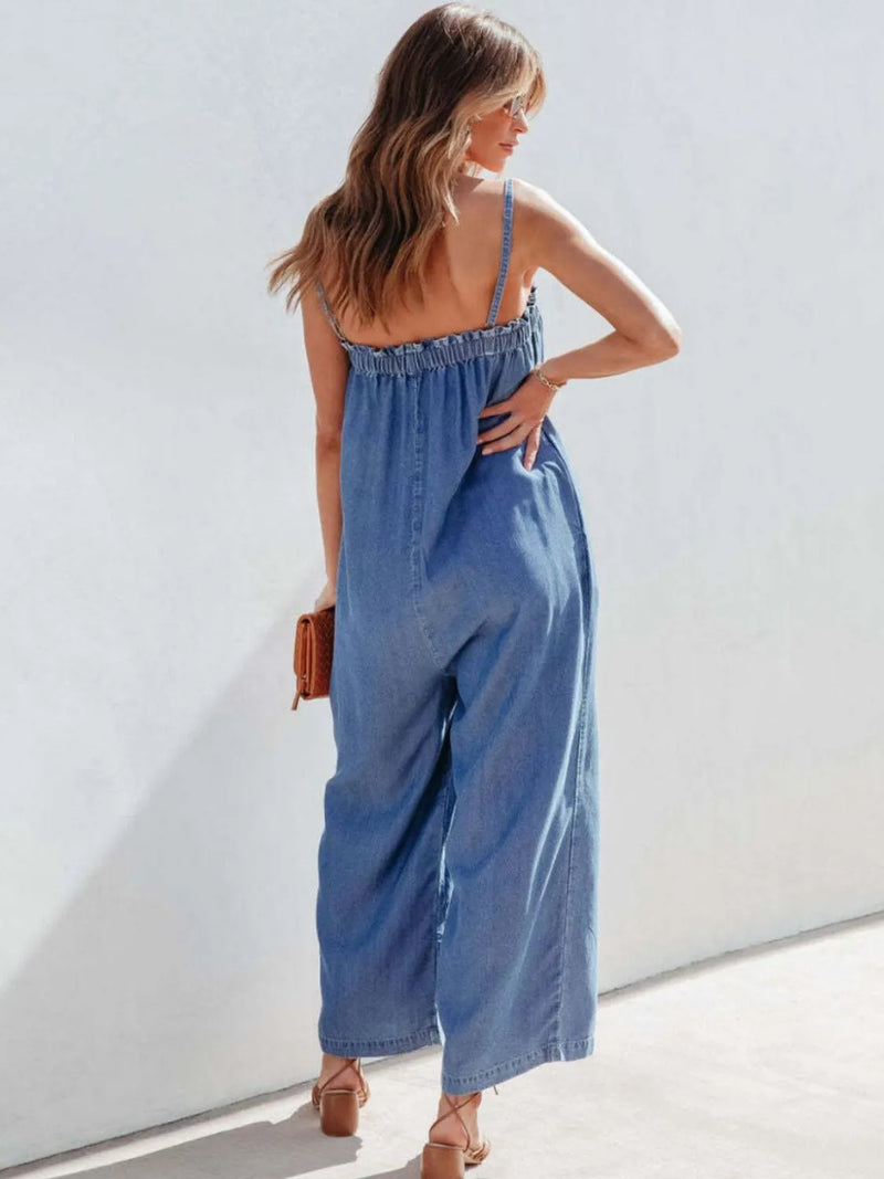Woman wearing a blue denim jumpsuit against a white background
